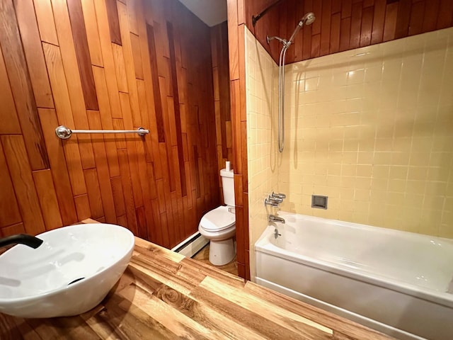 bathroom featuring a baseboard heating unit, tub / shower combination, wood walls, and toilet