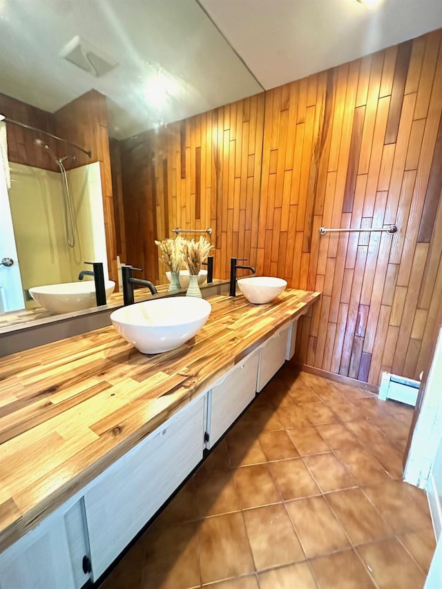 full bathroom with a baseboard heating unit, a shower, tile patterned flooring, and a sink