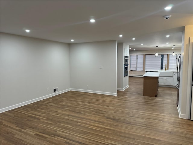 unfurnished living room with a sink, baseboards, dark wood-style floors, and recessed lighting