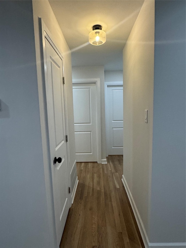 hallway featuring dark wood finished floors and baseboards