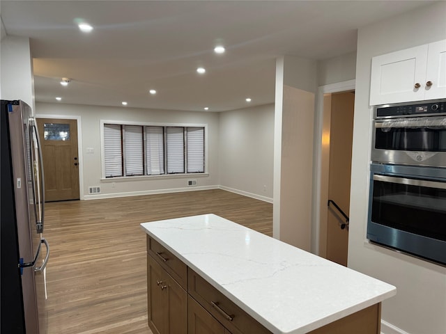 kitchen featuring light wood finished floors, recessed lighting, stainless steel appliances, white cabinets, and open floor plan