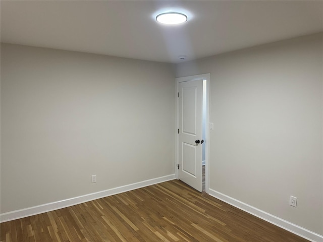 spare room featuring baseboards and dark wood-style floors