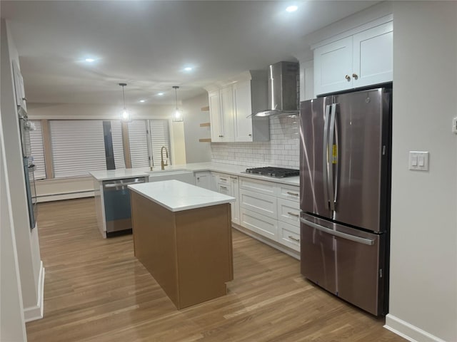 kitchen with a baseboard heating unit, stainless steel appliances, light wood-style floors, a peninsula, and wall chimney range hood