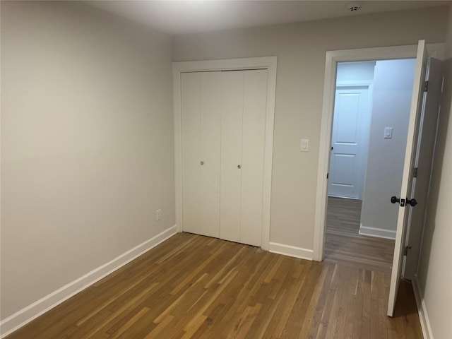 unfurnished bedroom with a closet, baseboards, and wood finished floors