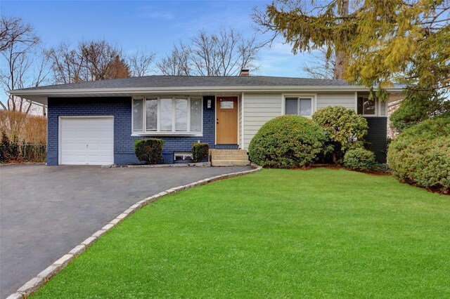 ranch-style house featuring brick siding, a front lawn, a chimney, a garage, and driveway