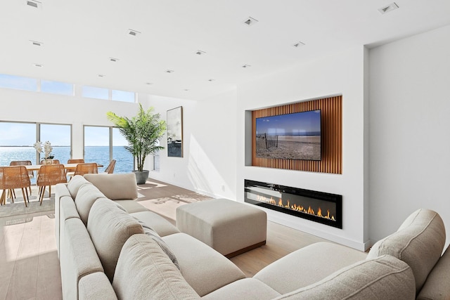 living area with a glass covered fireplace, wood finished floors, and visible vents