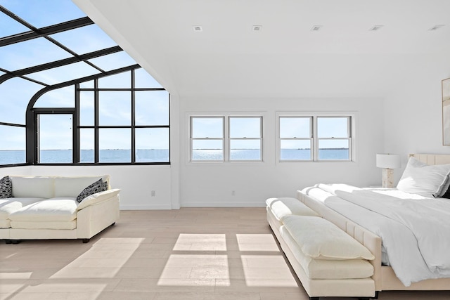 bedroom featuring baseboards, light wood-style floors, a water view, and a sunroom