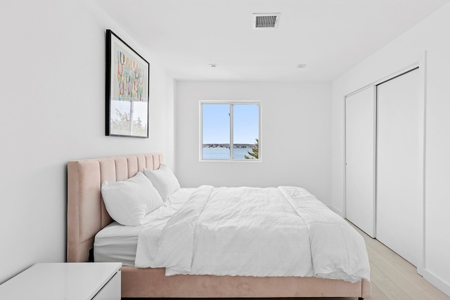 bedroom with a closet, visible vents, and light wood-style floors