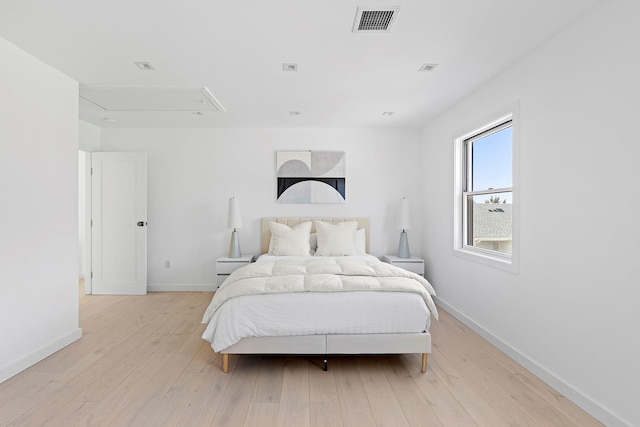 bedroom with visible vents, baseboards, attic access, and light wood-style flooring