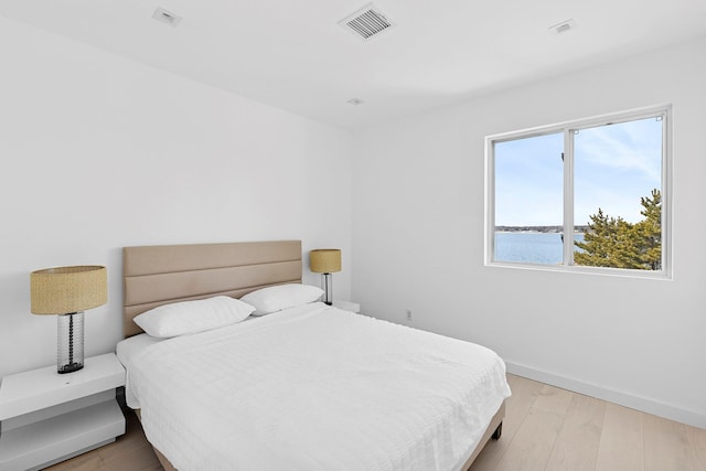 bedroom featuring light wood-style floors, visible vents, and baseboards