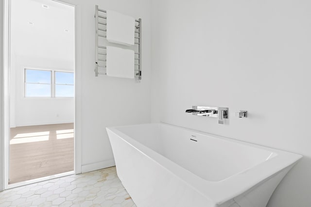 bathroom featuring tile patterned floors, radiator, and a freestanding bath