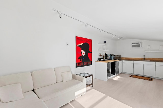 living room featuring vaulted ceiling, wine cooler, rail lighting, and light wood-type flooring