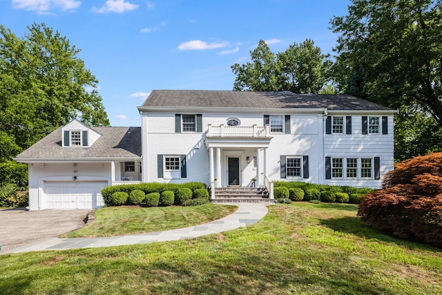 view of front of home with a garage, driveway, a front yard, and a balcony