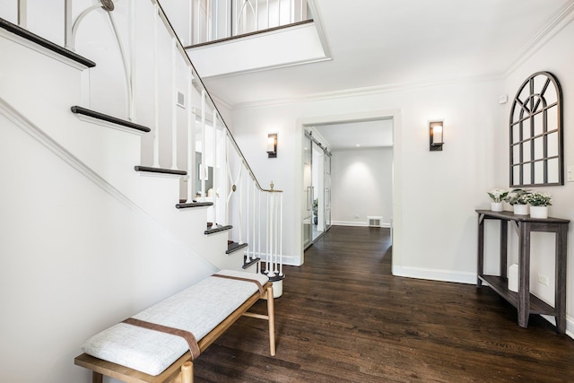 entryway with crown molding, a barn door, wood finished floors, and baseboards