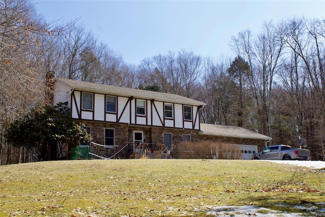 tudor home featuring a front lawn, a garage, stone siding, and stucco siding