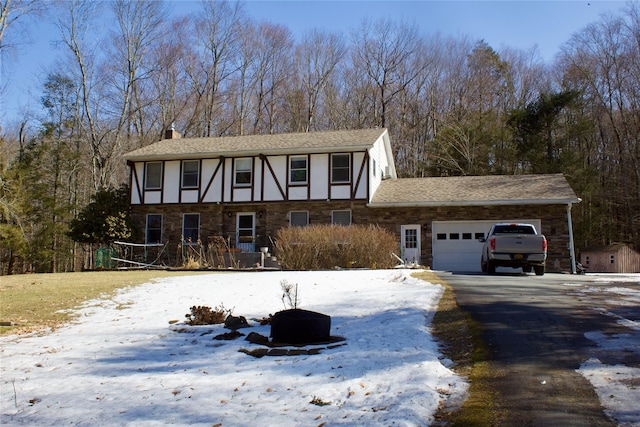 view of front facade with stucco siding, a garage, a chimney, and driveway