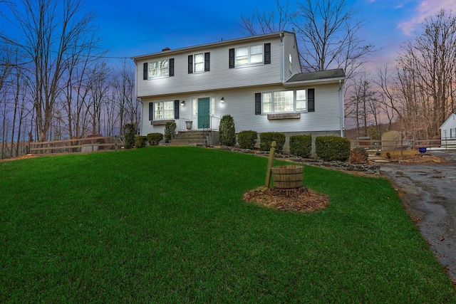 colonial-style house featuring a front lawn and fence