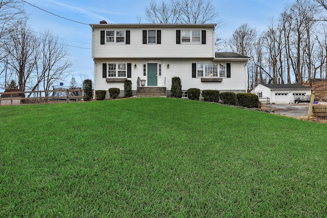 colonial-style house with an outdoor structure, a chimney, and a front lawn