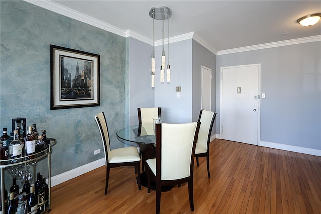 dining area featuring baseboards, wood finished floors, and ornamental molding