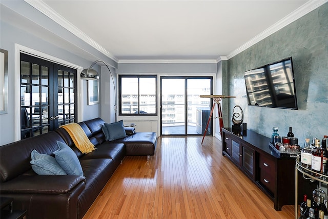 living area with light wood finished floors, crown molding, and french doors