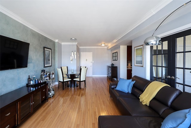 living area featuring light wood-style flooring, baseboards, crown molding, and french doors