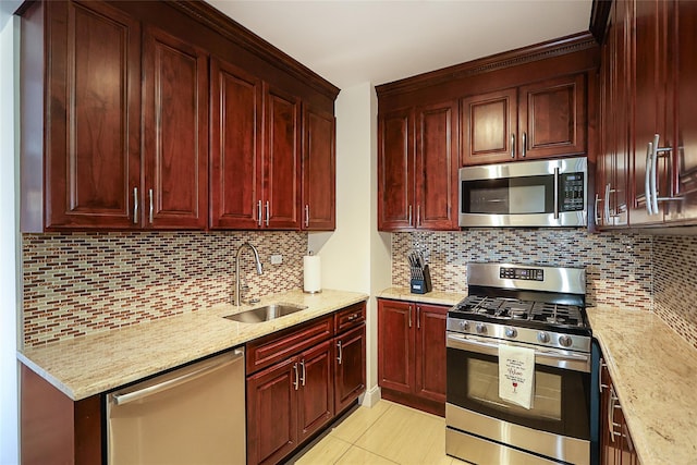 kitchen featuring light stone counters, appliances with stainless steel finishes, dark brown cabinets, and a sink