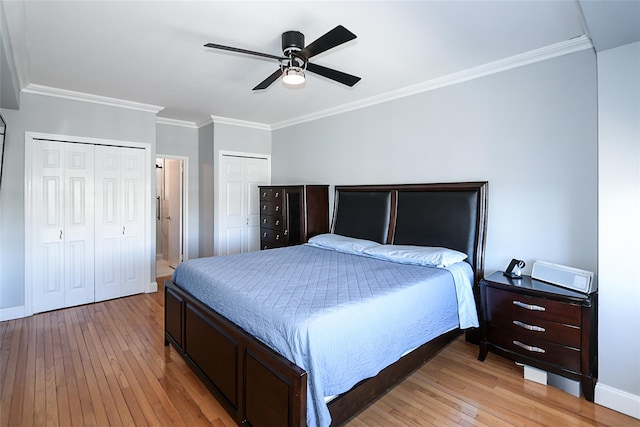 bedroom featuring crown molding, light wood-style flooring, and two closets