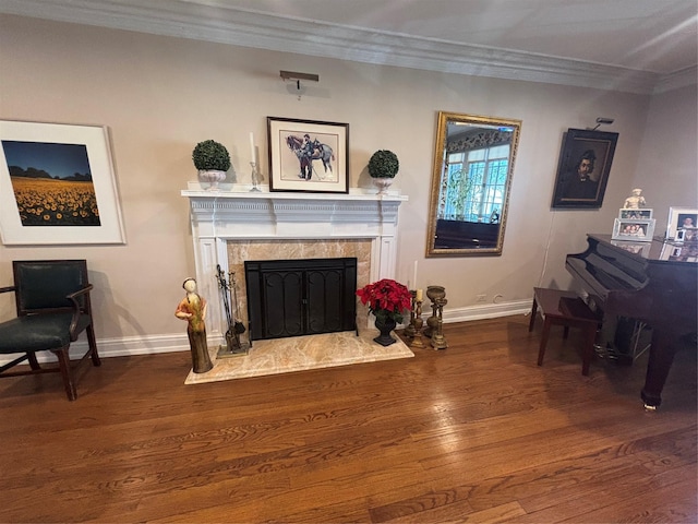 sitting room with baseboards, ornamental molding, wood finished floors, and a high end fireplace