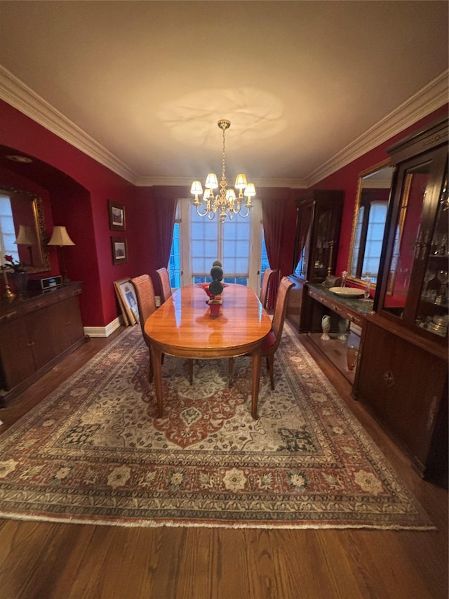 dining area featuring a notable chandelier, crown molding, baseboards, and wood finished floors