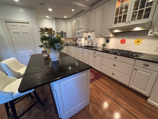 kitchen featuring dark wood finished floors, backsplash, a sink, white appliances, and under cabinet range hood