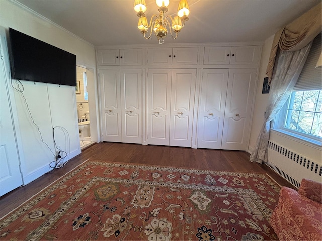 unfurnished bedroom featuring ornamental molding, dark wood-type flooring, radiator heating unit, and a notable chandelier