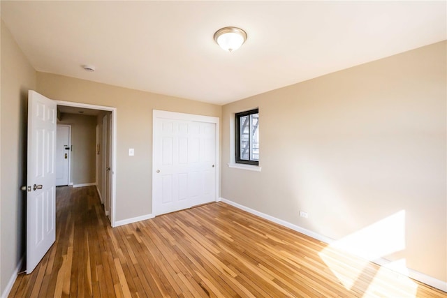 unfurnished bedroom with light wood-type flooring, baseboards, and a closet