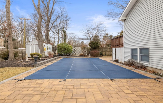 view of pool with a patio area, a storage unit, an outdoor structure, and a fenced backyard