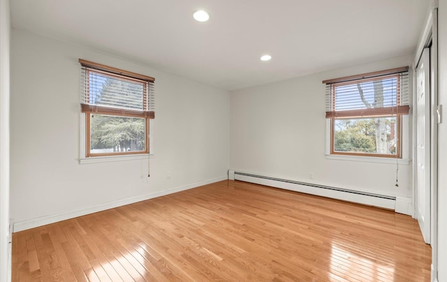 empty room with light wood-style flooring, baseboards, a baseboard heating unit, and recessed lighting
