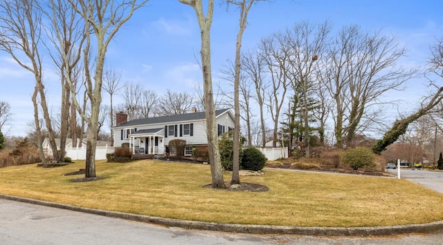 view of front of home featuring a front yard, fence, and a chimney