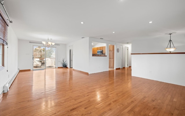 unfurnished living room with light wood finished floors, a baseboard radiator, a notable chandelier, and recessed lighting