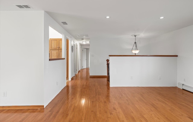 empty room with a baseboard radiator, recessed lighting, light wood finished floors, and visible vents