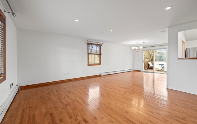 empty room with plenty of natural light, a baseboard radiator, and a notable chandelier