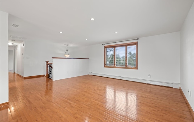 empty room featuring baseboard heating, light wood-style flooring, baseboards, visible vents, and recessed lighting