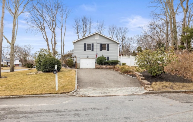 view of front of property featuring driveway, an attached garage, fence, and a front lawn