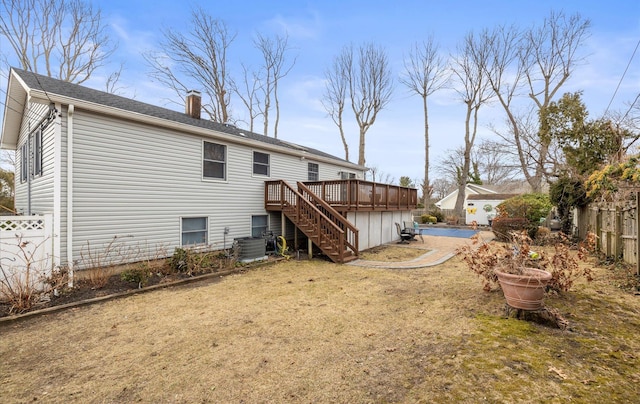 rear view of house featuring a wooden deck, a chimney, central AC, a fenced backyard, and stairway