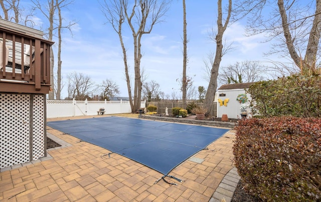 view of swimming pool featuring an outbuilding, a fenced backyard, a storage shed, and a patio area