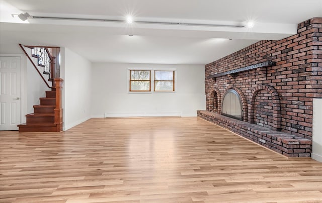 unfurnished living room with stairway, baseboards, light wood-style floors, a baseboard radiator, and a fireplace