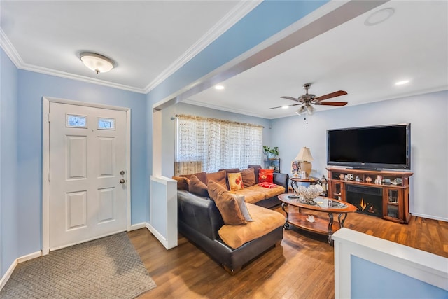 living area featuring baseboards, crown molding, and wood finished floors