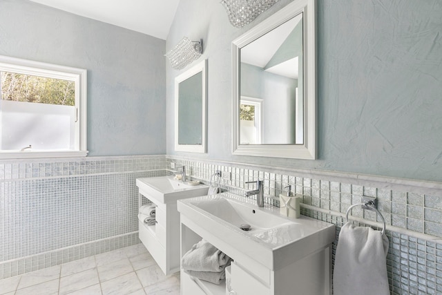 bathroom with tile walls, two sinks, and wainscoting