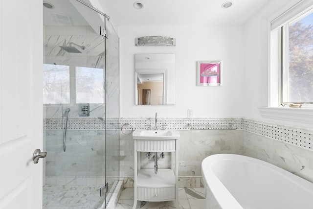 bathroom featuring a stall shower, a soaking tub, and a wealth of natural light