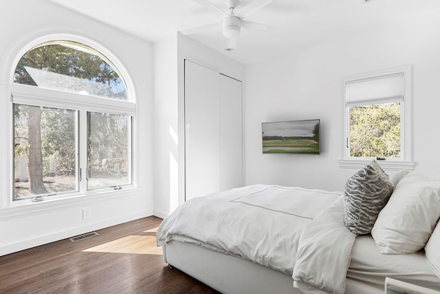 bedroom featuring ceiling fan, wood finished floors, visible vents, baseboards, and a closet