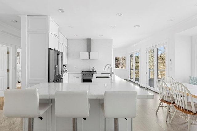 kitchen with ornamental molding, premium appliances, a sink, and white cabinetry