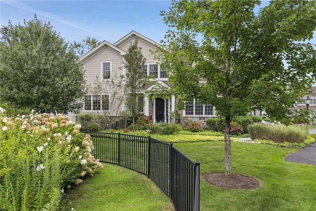 view of front of house featuring stone siding, fence, and a front yard