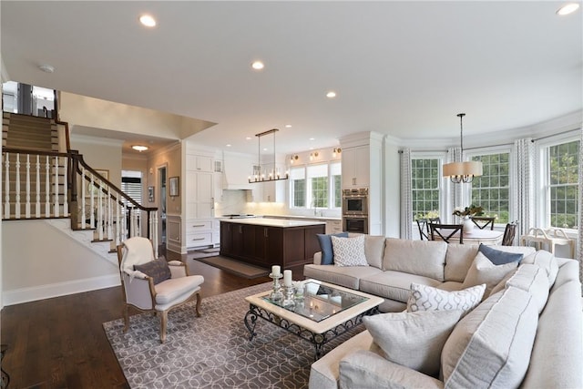 living room with dark wood-style flooring, stairway, baseboards, and an inviting chandelier